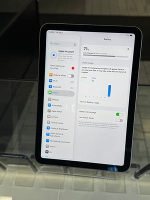 An Apple iPad displaying the Settings app on its screen, resting on a clear glass display stand.