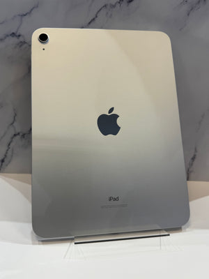 An Apple iPad shown from the back, featuring a silver finish with the iconic black Apple logo in the center and 'iPad' text on the right, resting on a white marble-patterned surface.