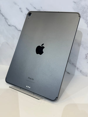 A gray Apple iPad Air standing upright on a clear display stand against a white marble-patterned background.