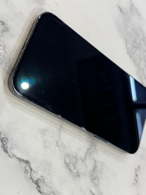 A black smartphone with a glossy screen lies diagonally on a white and gray marble-patterned surface.