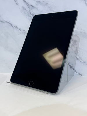 A black tablet device with a home button, shown standing upright on a clear acrylic display stand against a white marble-patterned background.