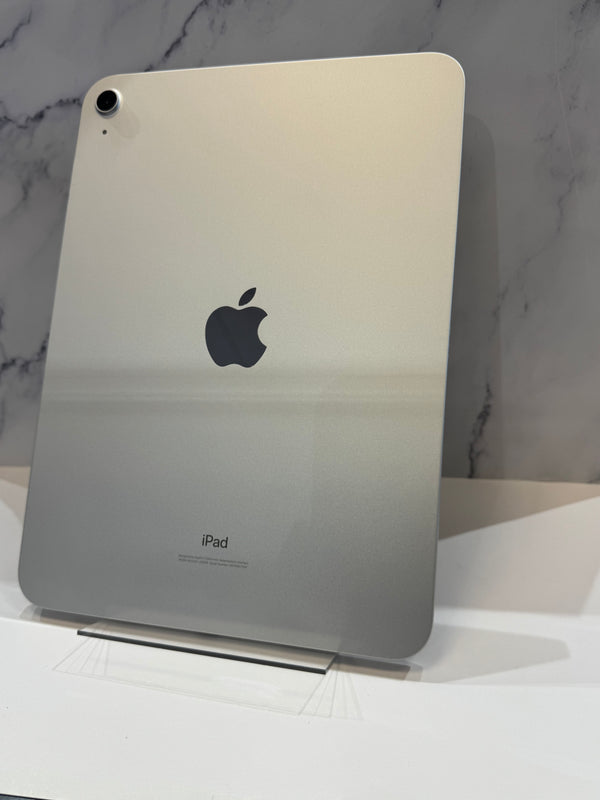 An Apple iPad with a metallic silver back panel, standing upright on a clear display stand against a gray marble-patterned background.