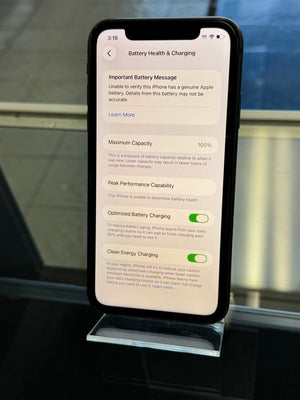 Phone screen displaying battery health information with a metallic object in the foreground.