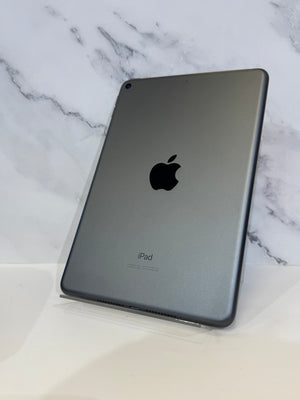 A gray Apple iPad shown from the back, standing upright on a clear display stand against a white marble-patterned background.