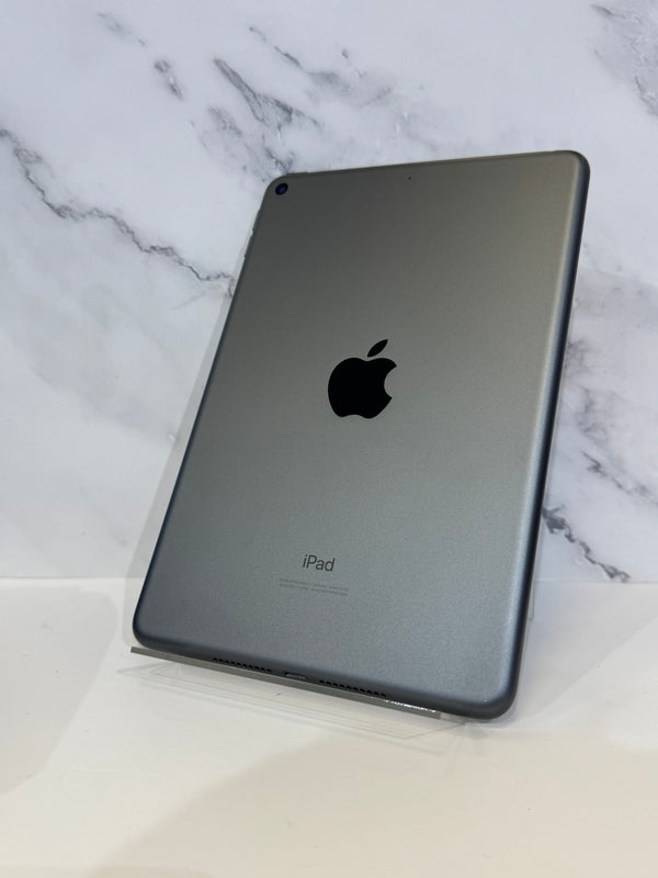 A gray Apple iPad shown from the back, standing upright on a clear display stand against a white marble-patterned background.