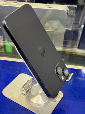 A black Apple iPhone 12 Pro shown from the back, resting on a clear display stand against a blue background.