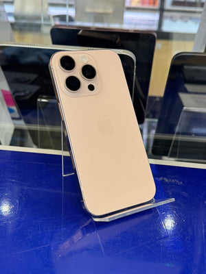 An iPhone Pro showing the back of the device with its triple-camera system, displayed on a clear stand on a blue counter.