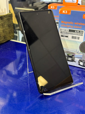 Black smartphone on a stand with a K3 magnetic wireless charging stand in the background.