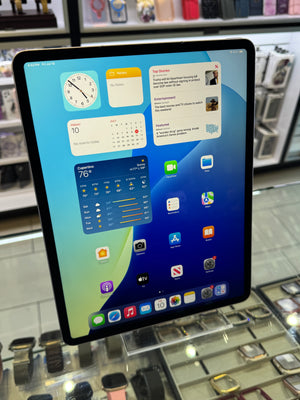 A tablet device with a black bezel and a colorful home screen, photographed in a retail or showroom environment with display cases visible in the background.