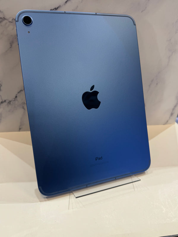 A blue Apple iPad shown from the back, standing upright on a clear display stand against a light marble-patterned background.