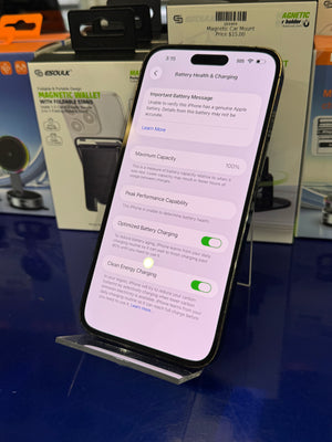 Smartphone displaying battery health and charging settings on a blue surface with packaging in the background