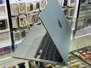 Silver laptop on display in a store with electronic equipment in the background