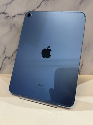 A blue Apple iPad shown from the back, standing on a clear stand against a light marble-patterned background.