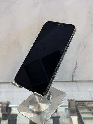 A black smartphone resting on a silver metal wall-mounted holder against a white marble-patterned wall.