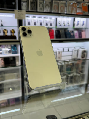 An Apple iPhone with a triple-camera system, displayed on a clear stand inside a retail store with shelves of other phones in the background.