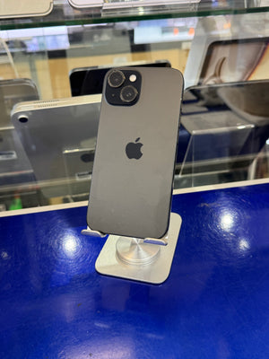 A dark gray Apple iPhone shown from the back, mounted on a small silver stand on a blue counter inside a retail display.
