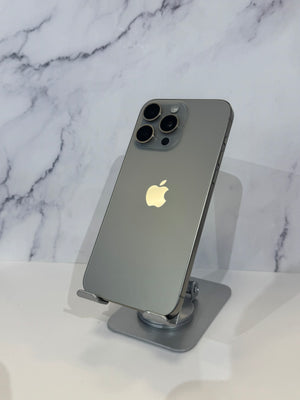 A gray Apple iPhone Pro shown from the back, resting on a silver metal stand against a white marble-patterned background.