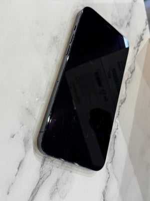A black smartphone with a glossy screen lies diagonally on a white marble-patterned surface.