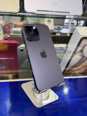 A dark gray Apple iPhone shown from the back, mounted on a display stand inside a retail store.