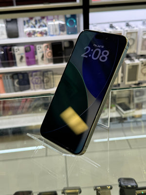 A silver iPhone with a black screen displaying the time 2:08, resting on a clear acrylic stand inside a retail store display.