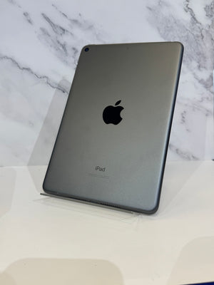 An Apple iPad in dark gray metallic finish, shown from the back resting on a clear acrylic stand against a white marble-patterned background.
