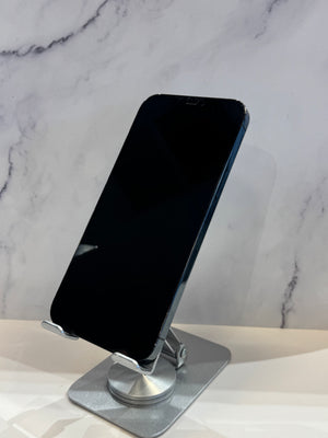 A black smartphone displayed upright on a silver metal stand against a light marble-patterned background.