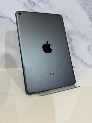 A dark gray Apple iPad standing upright on a clear acrylic display stand against a white marble-patterned background.