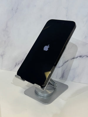 A black Apple iPhone with an Apple logo, displayed on a silver metal stand against a white marble-patterned background.