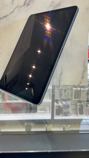 A black tablet with a dark screen, shown at an angle on a clear display stand in front of a marble-patterned background.