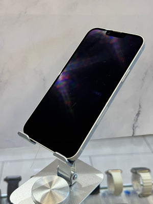 A silver smartphone with a black screen resting on a metallic stand, set against a light marble-patterned background.