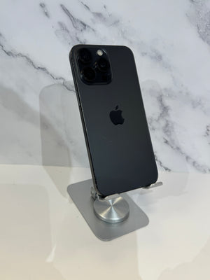 A black Apple iPhone Pro showing the back of the device, resting on a silver metal stand against a white and gray marble-patterned background.