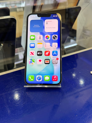 A black iPhone with its screen turned on, resting on a clear display stand on a glossy blue counter.