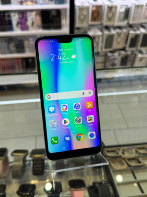 A black smartphone with a colorful gradient display on a clear acrylic stand inside a retail store.