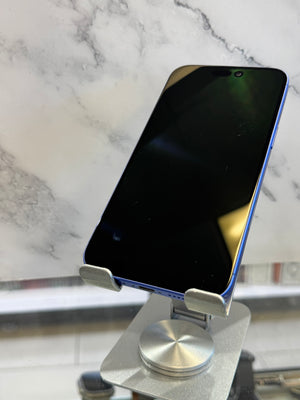 A blue-edged smartphone with a black screen rests on a silver metal stand against a white marble-patterned background.