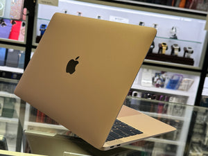 Gold laptop with Apple logo on a glass surface in a store setting