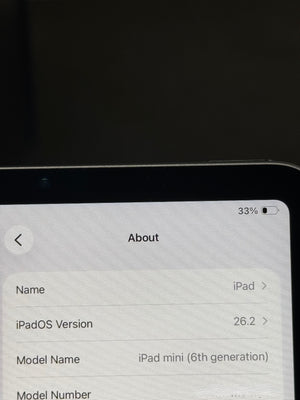 Close-up of a tablet screen showing the iPad About screen with iPadOS Version 26.2 and model name iPad mini (6th generation) on a dark background.