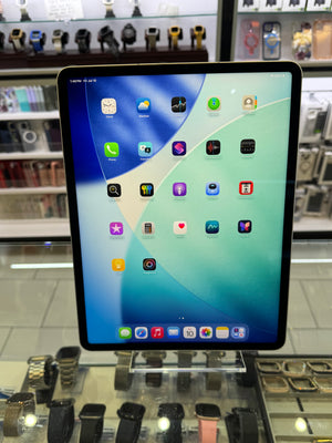 A tablet device with a black bezel and a colorful home screen, photographed inside a retail display area with other gadgets visible around it.