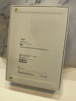 The back of a white rectangular product box, showing printed specifications and barcodes, standing on a white surface against a marble-patterned background.
