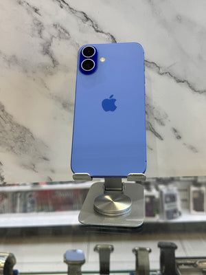 A blue Apple iPhone with a metallic finish, shown from the back on a silver metal display stand. The phone features a dual-camera system and the iconic Apple logo in the center.