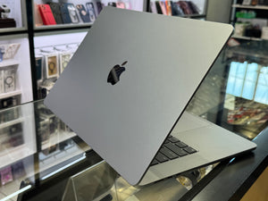 Silver laptop with Apple logo on a glass surface in a store setting