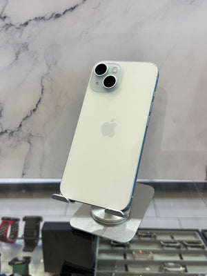 A white Apple iPhone 12 Pro shown from the back, resting on a silver metal display stand in front of a gray and white marble-patterned wall.