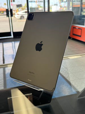 An Apple iPad Pro with a dark gray metallic finish, showing the back of the device with the Apple logo and 'iPad Pro' text, displayed on a stand in a store setting.