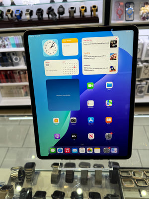An iPad displaying its home screen with various app icons, set against a blurred retail background filled with smartwatches.