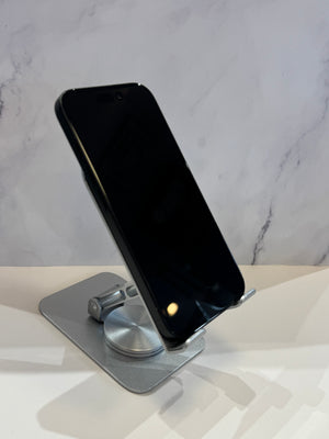 A black smartphone displayed at an angle on a metallic silver stand against a light gray marble-patterned background.
