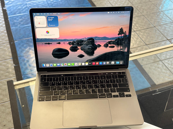Open laptop on a glass table with a scenic wallpaper