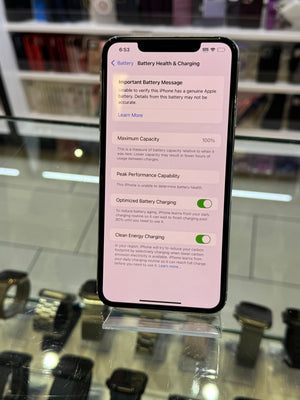 Smartphone displaying battery health screen on a reflective surface with blurred background