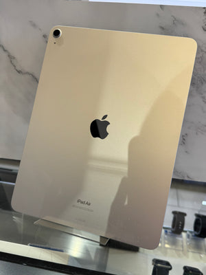 An Apple iPad Air shown from the back, resting on a glass display stand in a retail setting with a marble-patterned background.