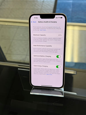 Smartphone displaying a battery health screen held by a stand on a reflective surface.