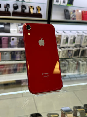 Red iPhone with Apple logo on a reflective surface in a store setting