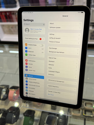 Tablet displaying settings menu on a glass surface with blurred background